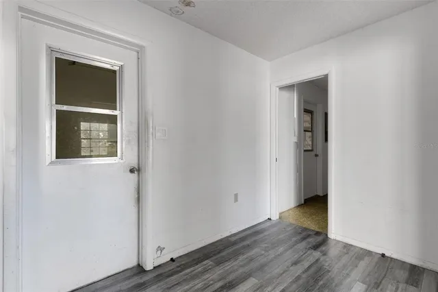 a view of an empty room with wooden floor and closet