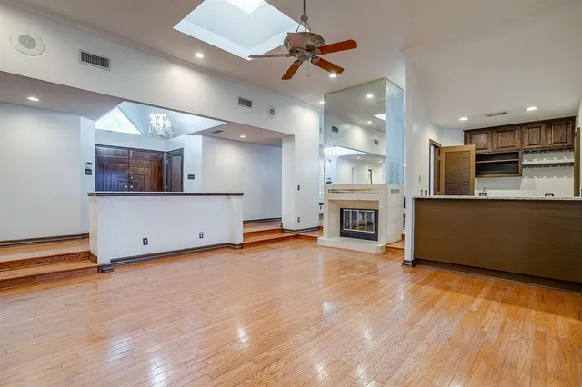 an empty room with wooden floor and a kitchen