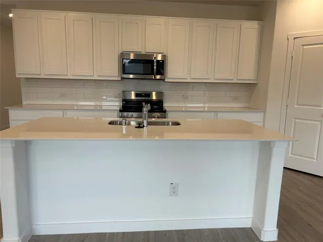 a view of kitchen with stove and white cabinets