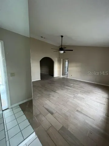 a view of empty room with window and chandelier fan
