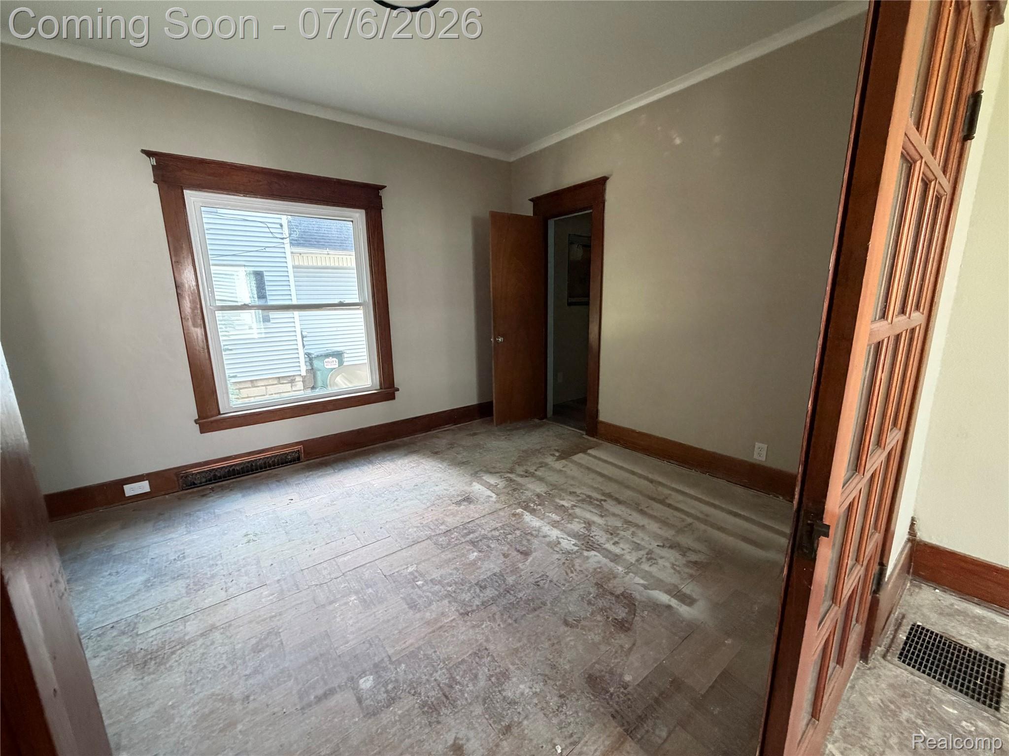 808 Division Street Owosso, MI 48867 - Photo 7 of 25 Room featuring a paneled wood door, wood trim, exposed flooring, and a single window