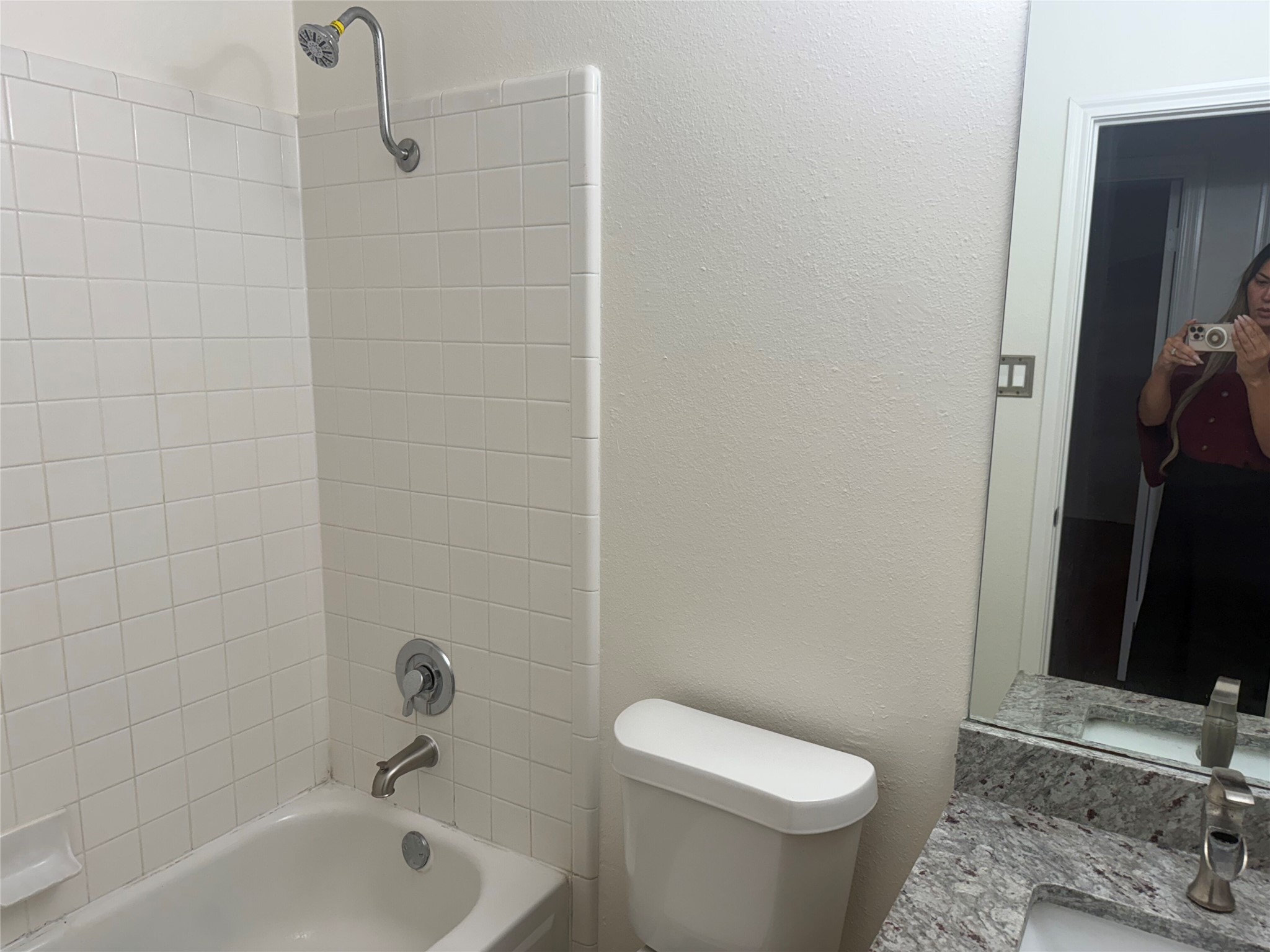 16910 Isle Of Man Road Pflugerville, TX 78660 - Photo 13 of 13 Bathroom featuring a white tiled shower/tub combination with chrome fixtures, a toilet, and a vanity with a granite-style countertop and undermount sink