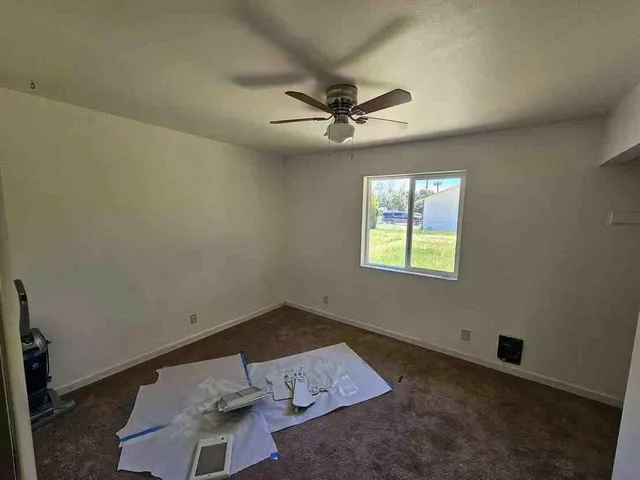 an empty room with a window and a ceiling fan