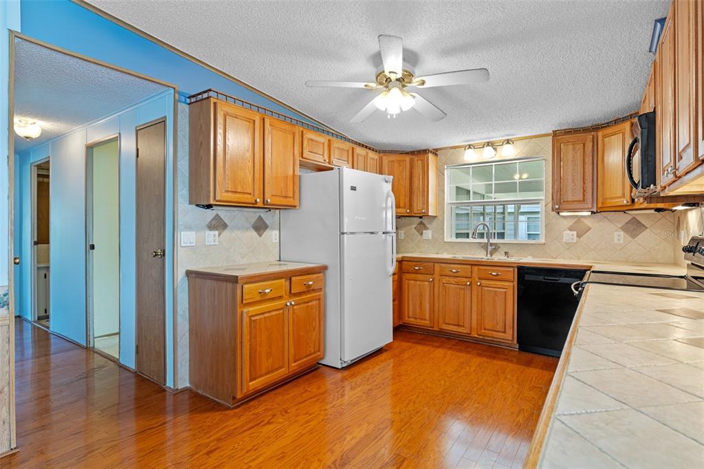 3026 Myakka River Road Tavares, FL 32778 - Photo 12 of 49 a kitchen with stainless steel appliances granite countertop a refrigerator a sink dishwasher a stove with wooden cabinets and floor