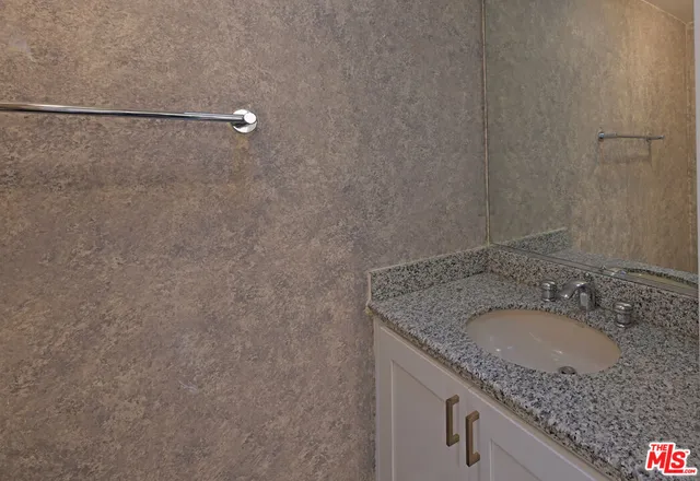 a bathroom with a granite countertop sink and a mirror