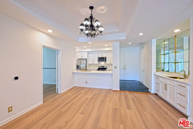 a large kitchen with kitchen island a stove a sink dishwasher a refrigerator and a oven with wooden floor