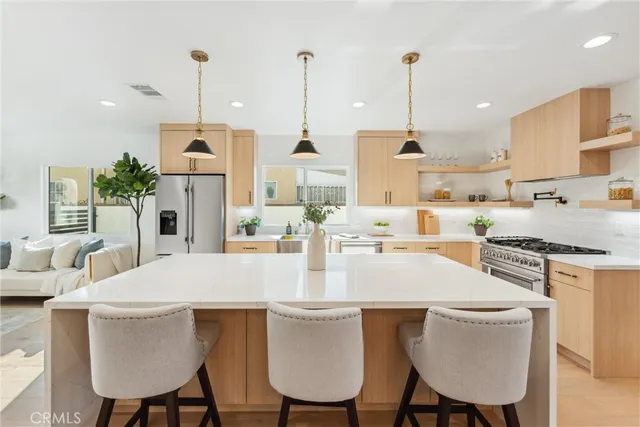 a view of kitchen with stainless steel appliances kitchen island granite countertop dining table chairs and sink