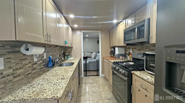 a kitchen with stainless steel appliances granite countertop a stove a sink and a microwave