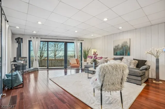 a living room with furniture large window and wooden floor
