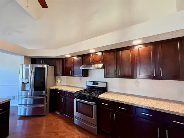 a kitchen with stainless steel appliances granite countertop a refrigerator stove and sink
