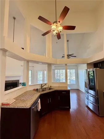 a view of kitchen with granite countertop a sink dishwasher a stove and a dining table with wooden floor
