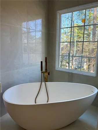 a white bath tub sitting in a bathroom next to a window