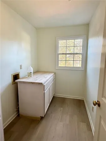 a view of an empty room with wooden floor fireplace and a window
