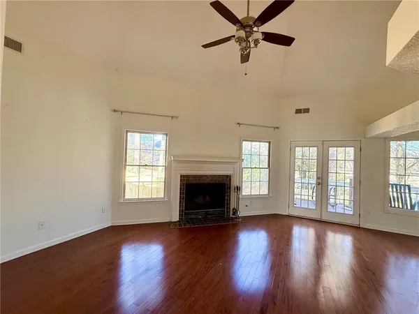 an empty room with windows fireplace and wooden floor