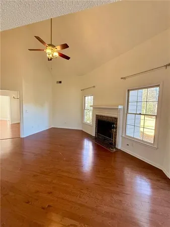 an empty room with wooden floor fireplace and windows