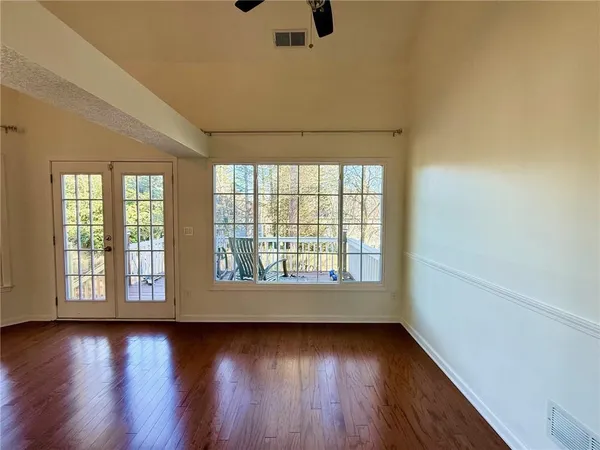 an empty room with wooden floor and windows