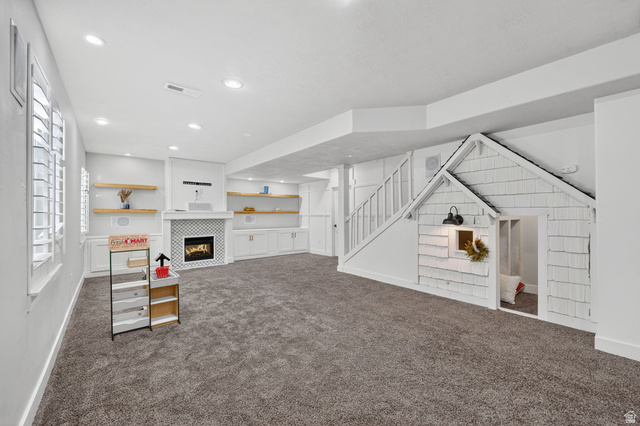 14714 South Bright Wood Road Herriman, UT 84096 - Photo 33 of 41 Unfurnished living room with a fireplace, dark colored carpet, and recessed lighting