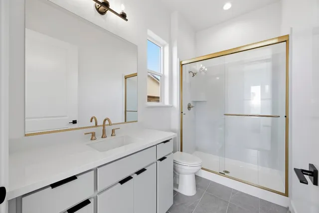 a bathroom with a shower sink vanity mirror and toilet