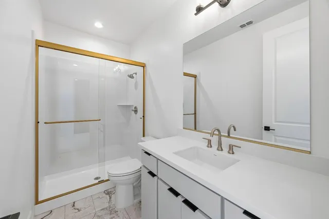 a bathroom with a shower sink vanity mirror and toilet