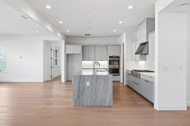 a large kitchen with stainless steel appliances granite countertop a stove a sink and a refrigerator