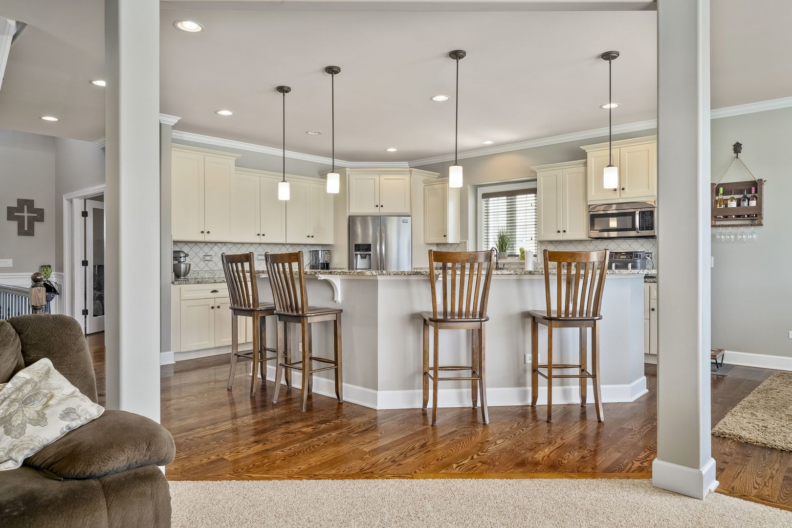 301 Arrowhead Drive Minooka, IL 60447 - Photo 16 of 43 a open kitchen with stainless steel appliances kitchen island granite countertop a refrigerator a stove a dining table and chairs with wooden floor