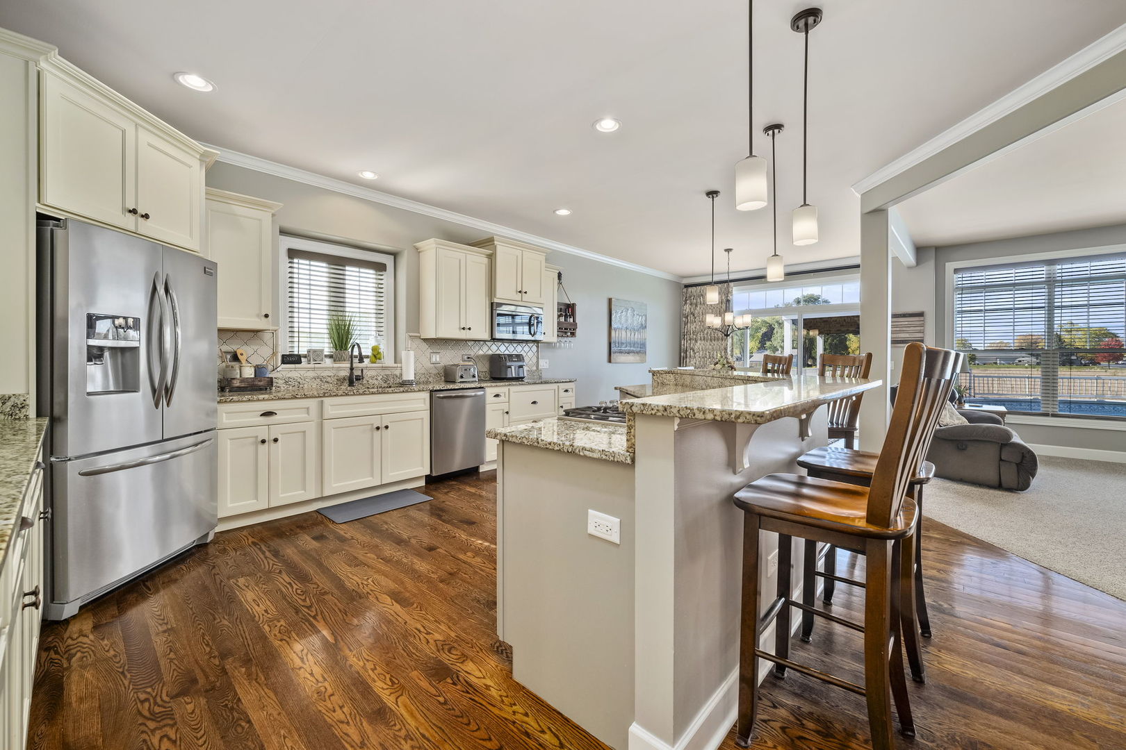 301 Arrowhead Drive Minooka, IL 60447 - Photo 9 of 43 a kitchen with stainless steel appliances kitchen island granite countertop a refrigerator a stove a sink a dining table and chairs with wooden floor