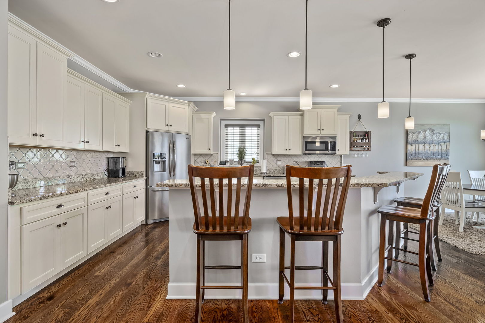 301 Arrowhead Drive Minooka, IL 60447 - Photo 10 of 43 a kitchen with stainless steel appliances kitchen island granite countertop a dining table chairs and white cabinets