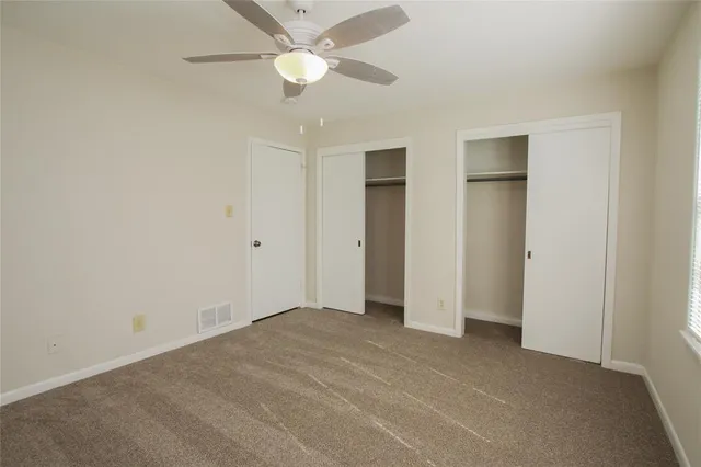 an empty room with closet and a ceiling fan