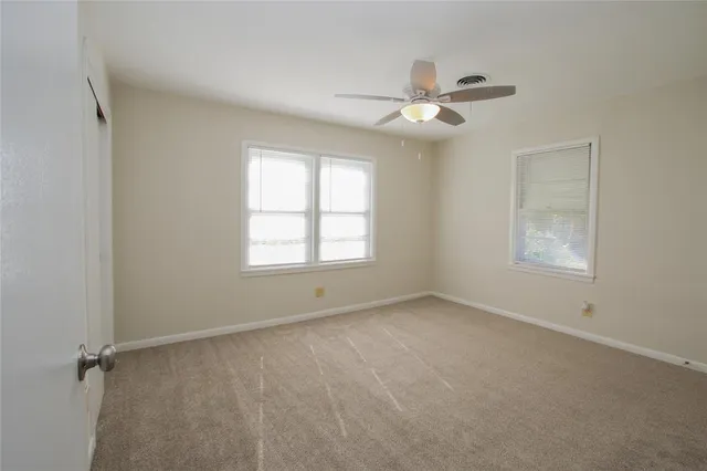 an empty room with windows and fan
