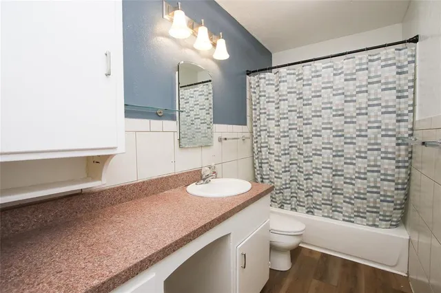 a bathroom with a granite countertop sink a toilet and a shower