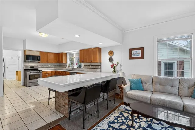 a living room with stainless steel appliances kitchen island granite countertop a stove a sink dishwasher and white cabinets with wooden floor