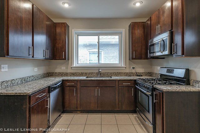 5331 West Addison Street Chicago, IL 60641 - Photo 11 of 32 a kitchen with stainless steel appliances granite countertop a stove a sink and a microwave