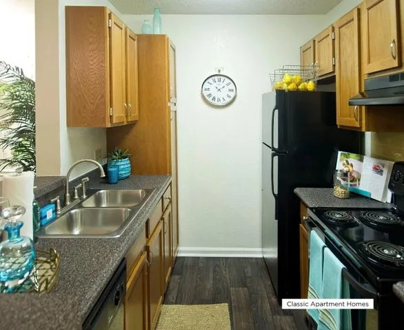 a kitchen with granite countertop a sink a stove and refrigerator