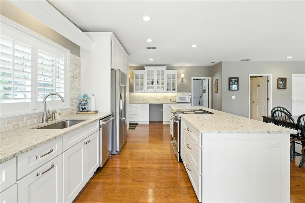 36641 Blanton Road Dade City, FL 33523 - Photo 22 of 76 a large kitchen with kitchen island a stove a sink a refrigerator and white cabinets with wooden floor