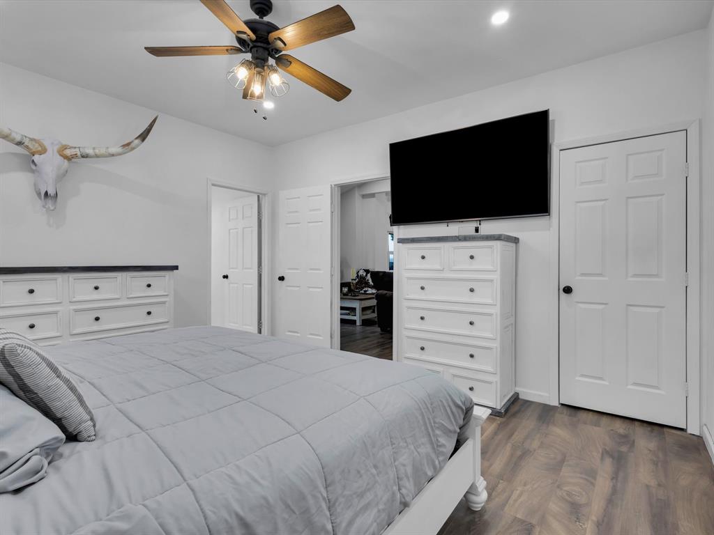 830 Louis Scherer Road Weatherford, TX 76088 - Photo 22 of 36 a bedroom with a bed a flat screen tv and a chandelier