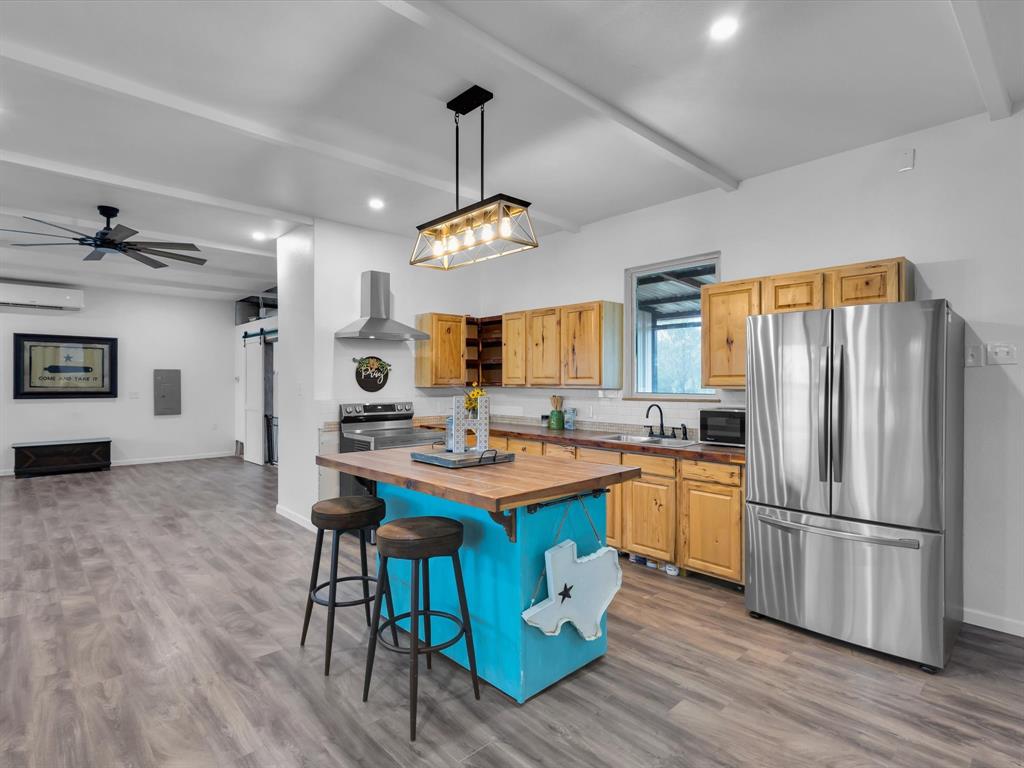 830 Louis Scherer Road Weatherford, TX 76088 - Photo 8 of 36 a kitchen with stainless steel appliances granite countertop a refrigerator a stove a sink dishwasher a dining table and chairs with wooden floor