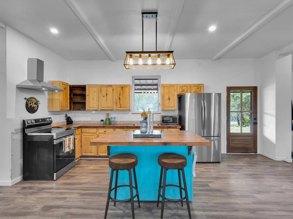 830 Louis Scherer Road Weatherford, TX 76088 - Photo 9 of 36 a kitchen with stainless steel appliances granite countertop a stove top oven a refrigerator a sink dishwasher a dining table and chairs with wooden floor