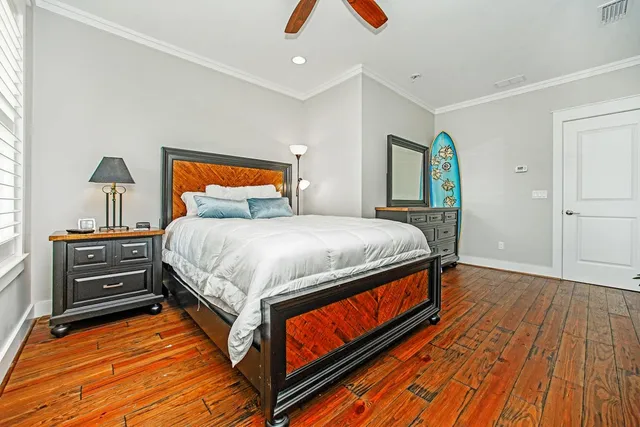 a bedroom with a bed and a dresser with wooden floor