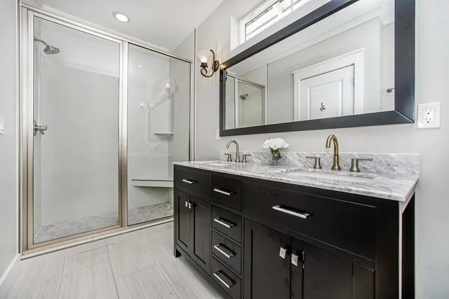 a bathroom with a granite countertop sink a mirror a vanity and shower