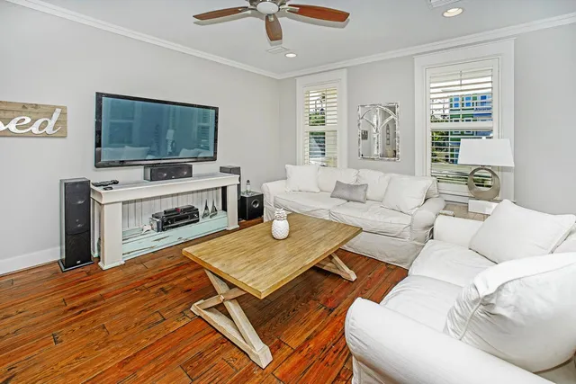 a living room with furniture a flat screen tv and a refrigerator