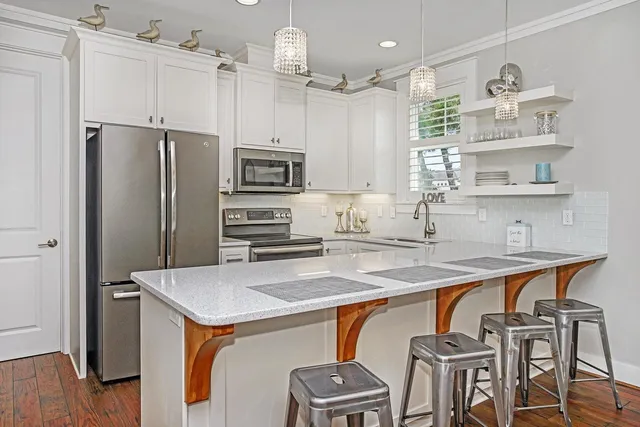 a kitchen with stainless steel appliances a refrigerator a sink a stove a table and chairs