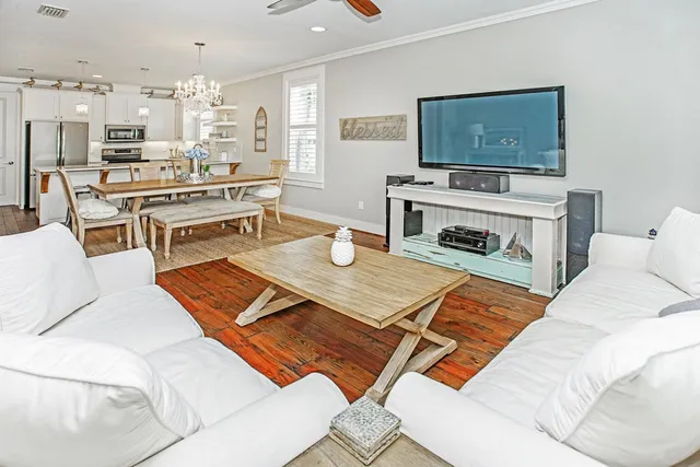 a living room with furniture a flat screen tv and kitchen view