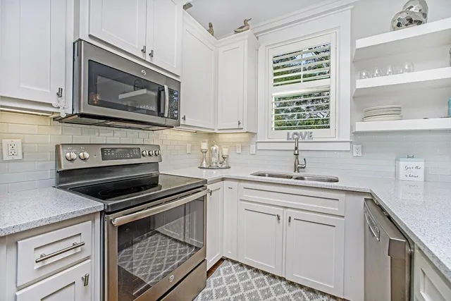 a kitchen with cabinets stainless steel appliances a sink and a window