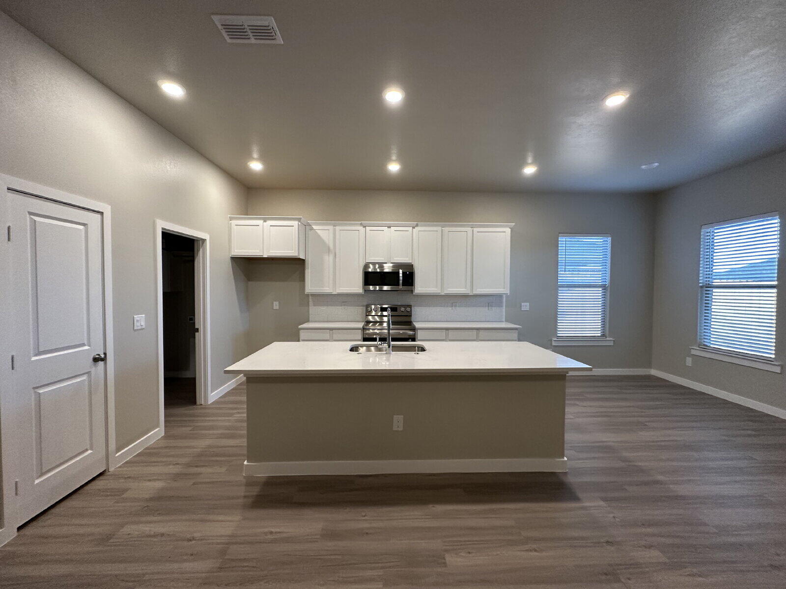 2005 135th Street Lubbock, TX 79423 - Photo 4 of 13 a view of a kitchen with kitchen island a sink wooden floor and a refrigerator
