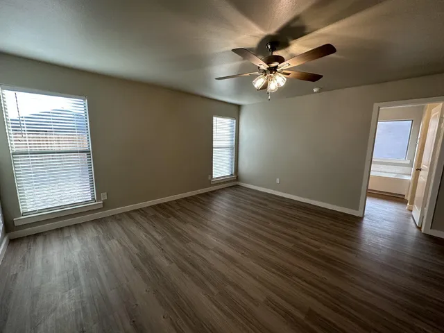 a view of empty room with wooden floor and fan