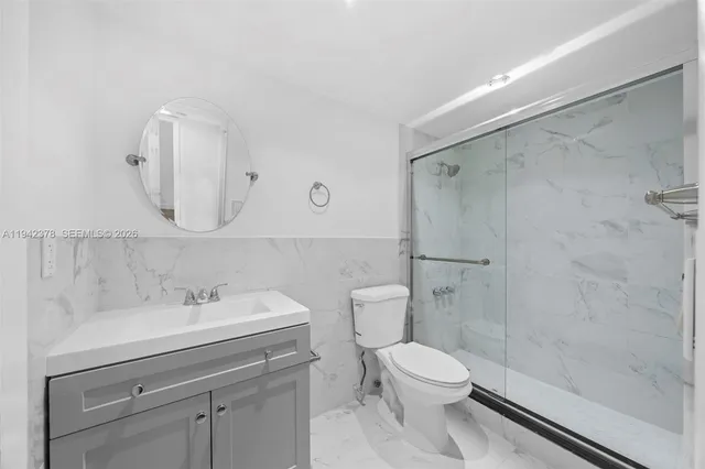 a bathroom with a toilet a sink a mirror and shower