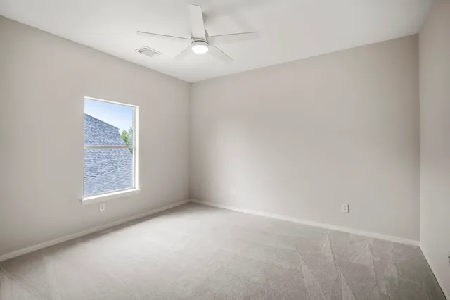 an empty room with a window and ceiling fan