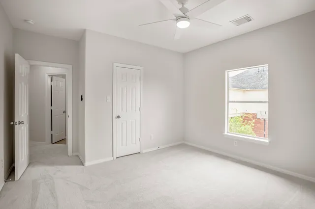 an empty room with a window and a fan