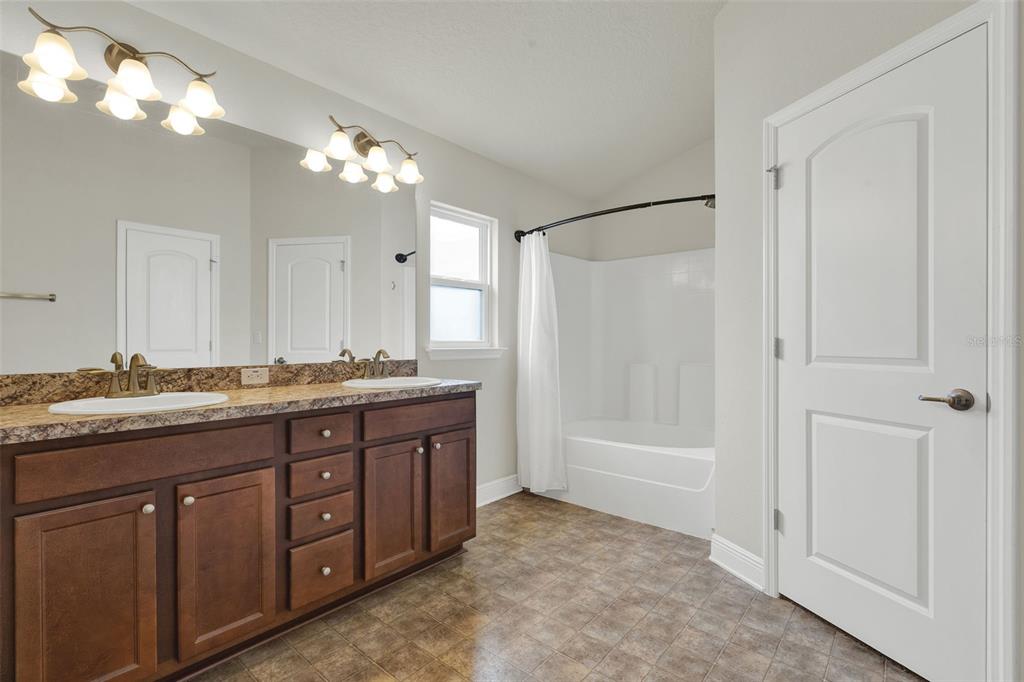 4229 Barnsley Lane Tavares, FL 32778 - Photo 16 of 20 a bathroom with a granite countertop sink a large mirror and a bathtub
