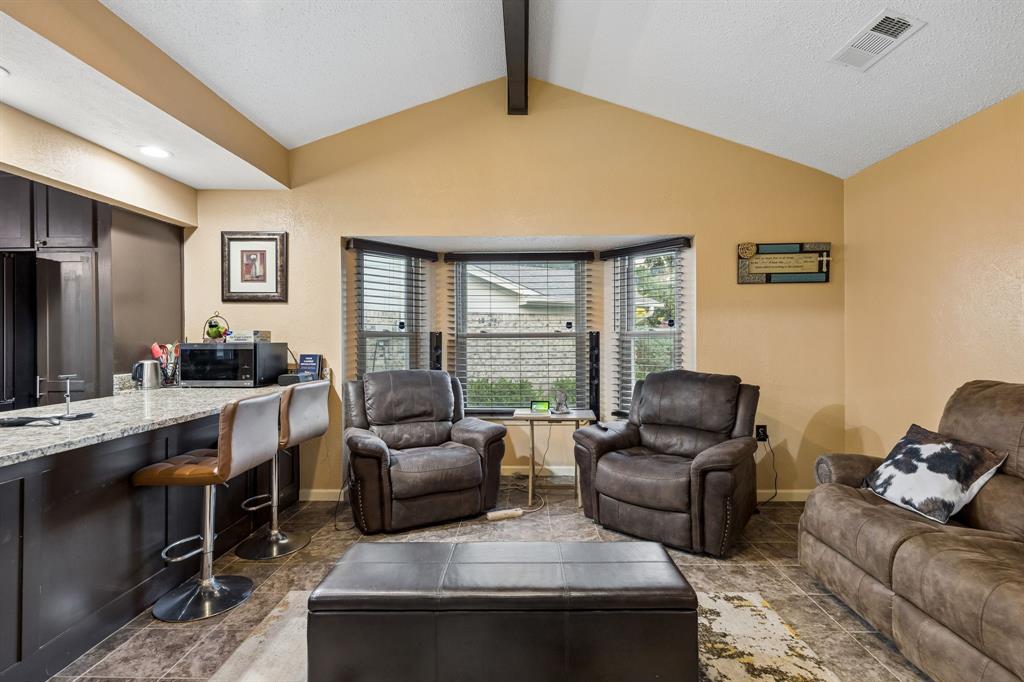 2617 Quail Ridge Irving, TX 75060 - Photo 10 of 17 Spacious living area featuring a vaulted ceiling with exposed beam, a bay window with blinds, and durable tile flooring